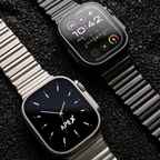 Two Apex smartwatches with metallic links are displayed on a dark textured background. One watch features a black dial with silver-tone hands and markers, while the other features a black digital watch face with colorful app icons.